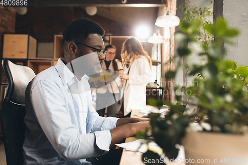 Image of Colleagues working together in modern office using devices and gadgets during negotiations