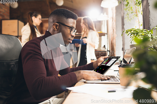 Image of Colleagues working together in modern office using devices and gadgets during negotiations