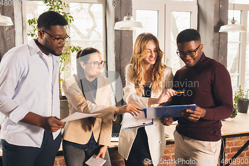 Image of Colleagues working together in modern office using devices and gadgets during negotiations