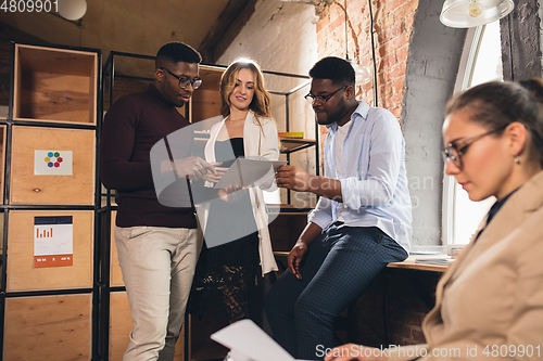 Image of Colleagues working together in modern office using devices and gadgets during negotiations