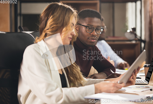 Image of Colleagues working together in modern office using devices and gadgets during negotiations