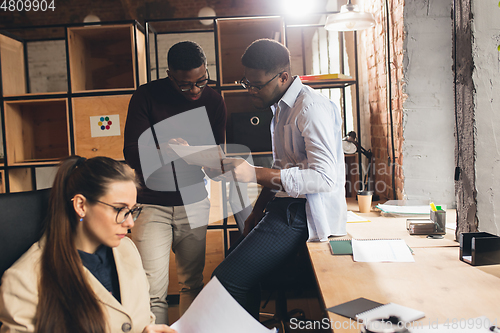 Image of Colleagues working together in modern office using devices and gadgets during negotiations