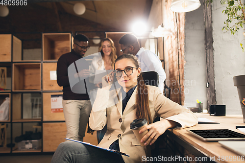 Image of Colleagues working together in modern office using devices and gadgets during negotiations