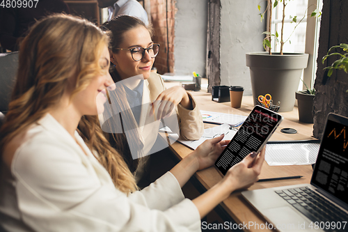 Image of Colleagues working together in modern office using devices and gadgets during negotiations