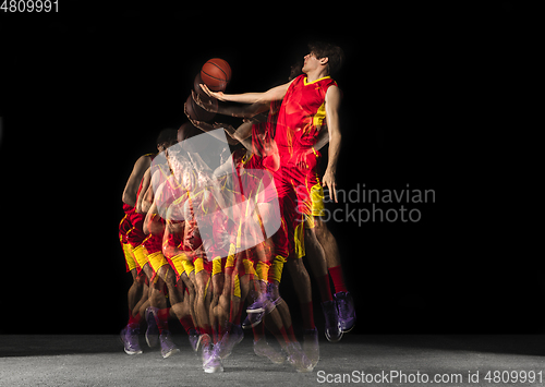 Image of Young caucasian basketball player in motion and action in mixed light on dark background. Concept of healthy lifestyle, professional sport, hobby.