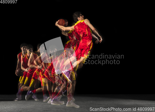 Image of Young caucasian basketball player in motion and action in mixed light on dark background. Concept of healthy lifestyle, professional sport, hobby.