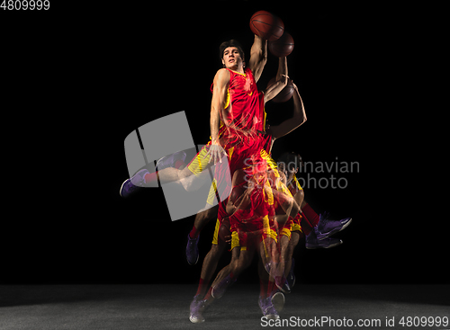 Image of Young caucasian basketball player in motion and action in mixed light on dark background. Concept of healthy lifestyle, professional sport, hobby.