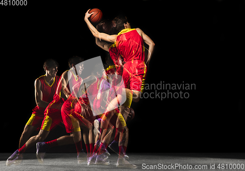 Image of Young caucasian basketball player in motion and action in mixed light on dark background. Concept of healthy lifestyle, professional sport, hobby.