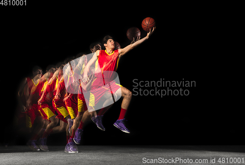 Image of Young caucasian basketball player in motion and action in mixed light on dark background. Concept of healthy lifestyle, professional sport, hobby.