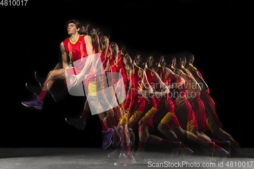 Image of Young caucasian basketball player in motion and action in mixed light on dark background. Concept of healthy lifestyle, professional sport, hobby.