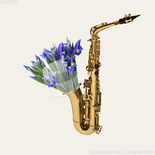 Image of Contemporary art collage, modern design. Retro style. Saxophone with bouquet of blooming spring flowers on pastel background