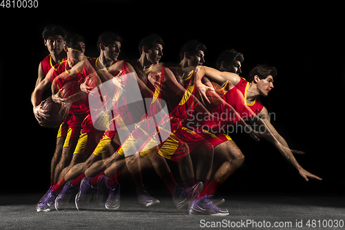 Image of Young caucasian basketball player in motion and action in mixed light on dark background. Concept of healthy lifestyle, professional sport, hobby.