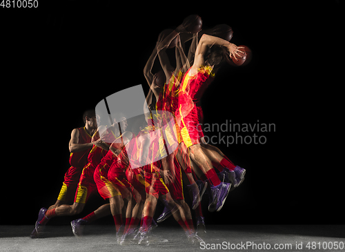 Image of Young caucasian basketball player in motion and action in mixed light on dark background. Concept of healthy lifestyle, professional sport, hobby.