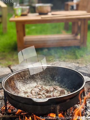 Image of gourmet beef stew cooked in cauldron on outdoor fire pit