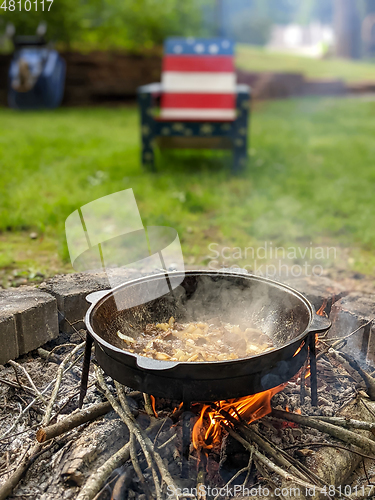 Image of gourmet beef stew cooked in cauldron on outdoor fire pit