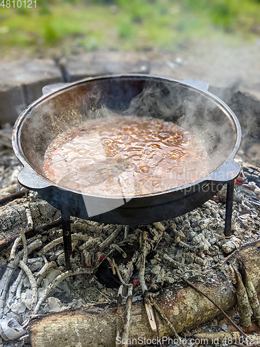 Image of gourmet beef stew cooked in cauldron on outdoor fire pit