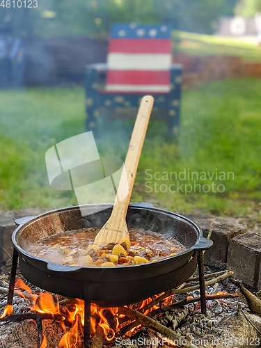 Image of gourmet beef stew cooked in cauldron on outdoor fire pit