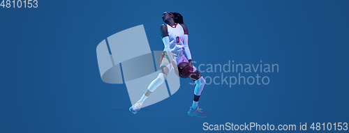 Image of Beautiful african-american female basketball player in motion and action in neon light on blue background. Concept of healthy lifestyle, professional sport, hobby.