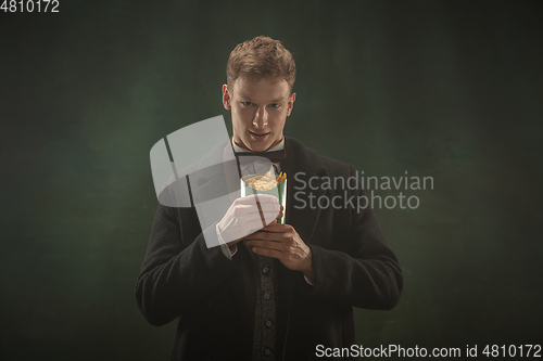 Image of Young man in art action isolated on dark green background. Retro style, comparison of eras concept.