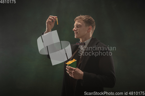 Image of Young man in art action isolated on dark green background. Retro style, comparison of eras concept.