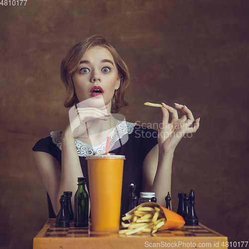 Image of Young woman in art action isolated on brown background. Retro style, comparison of eras concept.