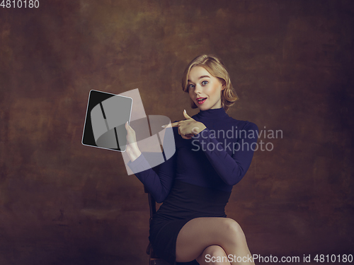 Image of Young woman in art action isolated on brown background. Retro style, comparison of eras concept.