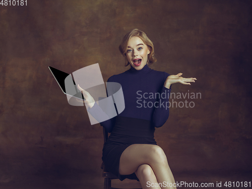 Image of Young woman in art action isolated on brown background. Retro style, comparison of eras concept.