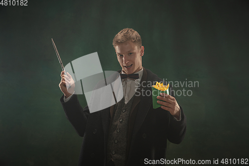 Image of Young man in art action isolated on dark green background. Retro style, comparison of eras concept.