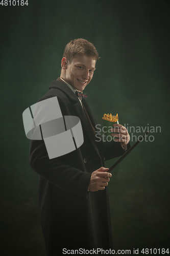 Image of Young man in art action isolated on dark green background. Retro style, comparison of eras concept.