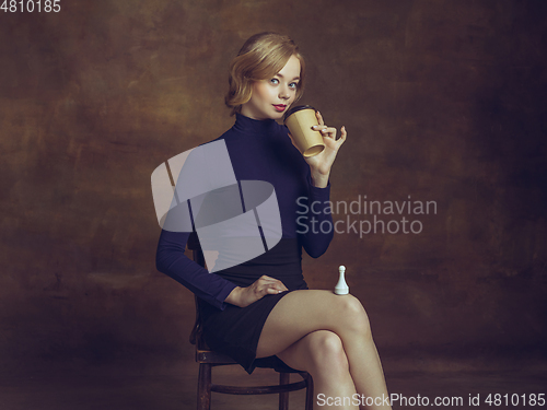 Image of Young woman in art action isolated on brown background. Retro style, comparison of eras concept.