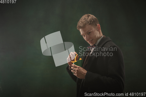 Image of Young man in art action isolated on dark green background. Retro style, comparison of eras concept.