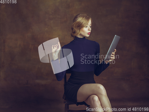 Image of Young woman in art action isolated on brown background. Retro style, comparison of eras concept.