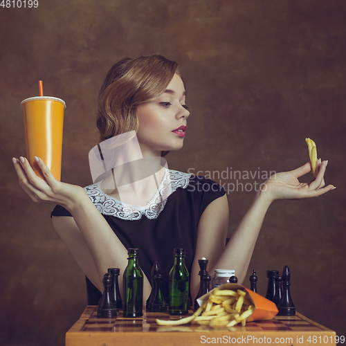 Image of Young woman in art action isolated on brown background. Retro style, comparison of eras concept.