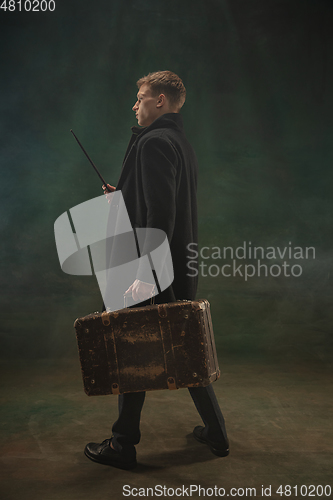 Image of Young man in art action isolated on dark green background. Retro style, comparison of eras concept.