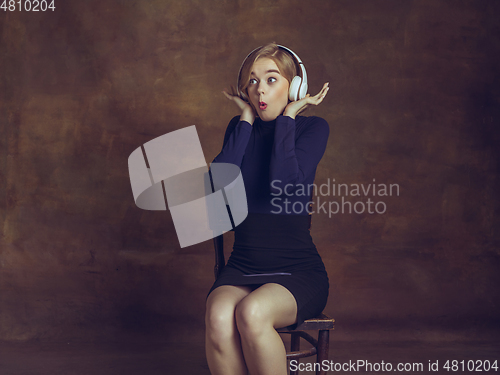 Image of Young woman in art action isolated on brown background. Retro style, comparison of eras concept.