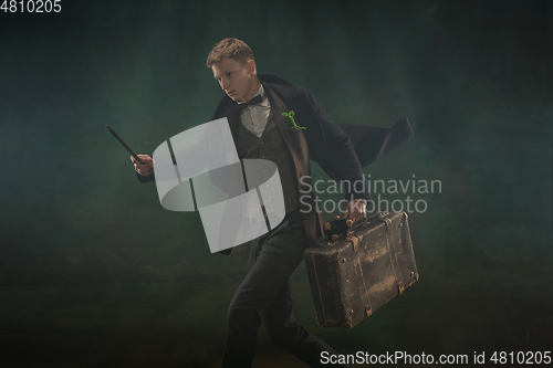 Image of Young man in art action isolated on dark green background. Retro style, comparison of eras concept.