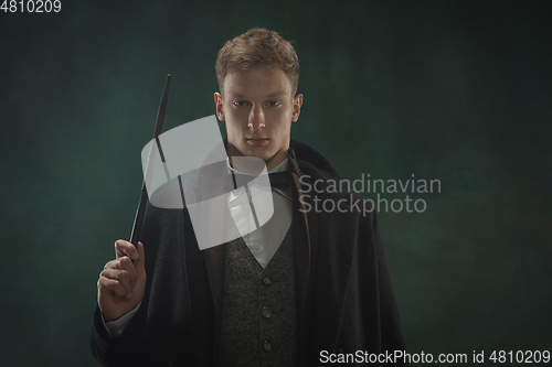 Image of Young man in art action isolated on dark green background. Retro style, comparison of eras concept.