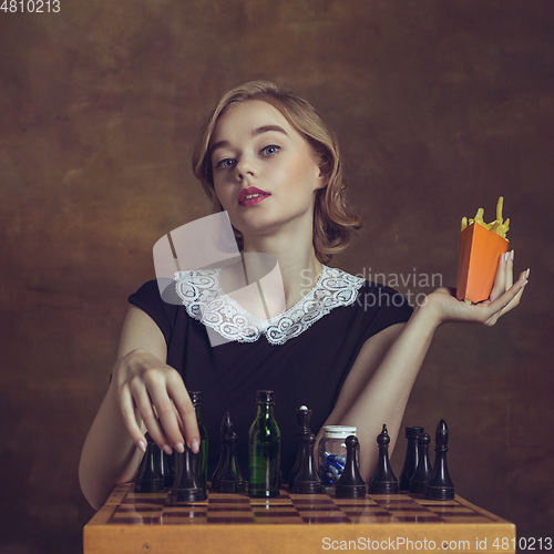 Image of Young woman in art action isolated on brown background. Retro style, comparison of eras concept.