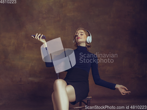 Image of Young woman in art action isolated on brown background. Retro style, comparison of eras concept.