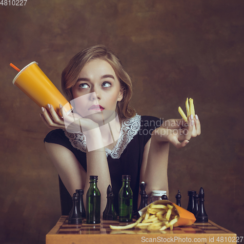 Image of Young woman in art action isolated on brown background. Retro style, comparison of eras concept.