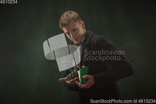 Image of Young man in art action isolated on dark green background. Retro style, comparison of eras concept.