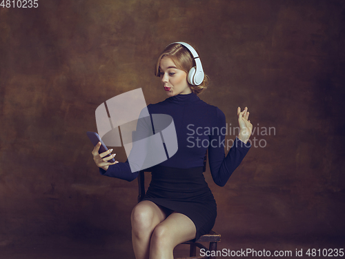 Image of Young woman in art action isolated on brown background. Retro style, comparison of eras concept.