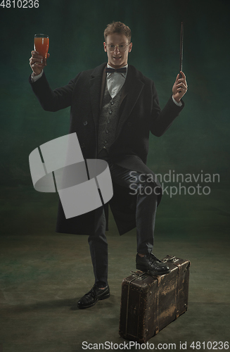 Image of Young man in art action isolated on dark green background. Retro style, comparison of eras concept.