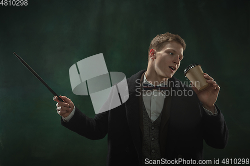 Image of Young man in art action isolated on dark green background. Retro style, comparison of eras concept.