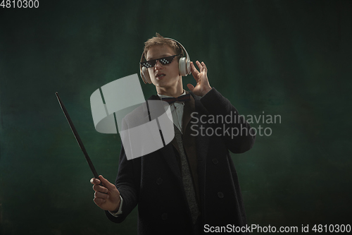 Image of Young man in art action isolated on dark green background. Retro style, comparison of eras concept.