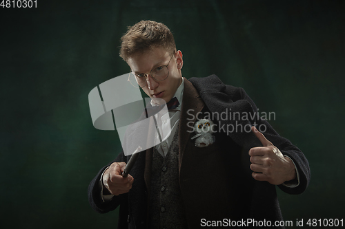 Image of Young man in art action isolated on dark green background. Retro style, comparison of eras concept.