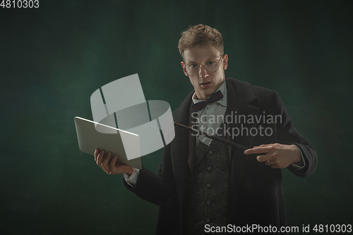 Image of Young man in art action isolated on dark green background. Retro style, comparison of eras concept.