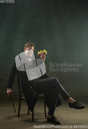 Image of Young man in art action isolated on dark green background. Retro style, comparison of eras concept.