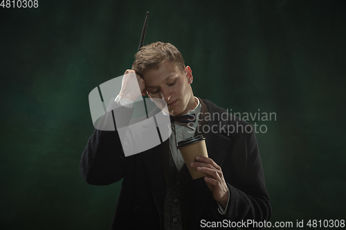 Image of Young man in art action isolated on dark green background. Retro style, comparison of eras concept.