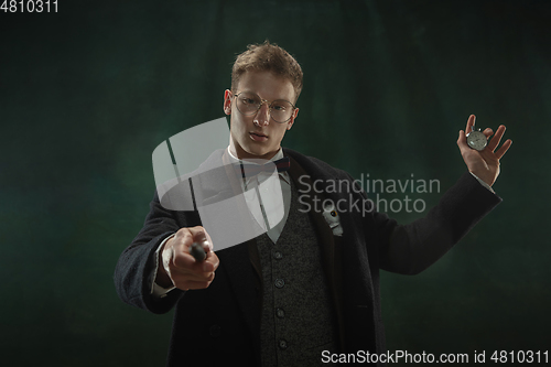 Image of Young man in art action isolated on dark green background. Retro style, comparison of eras concept.